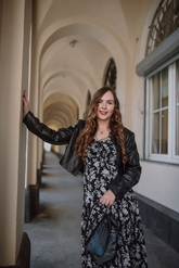 a lady in a black floral printed dress and an eco-friendly leather jacket